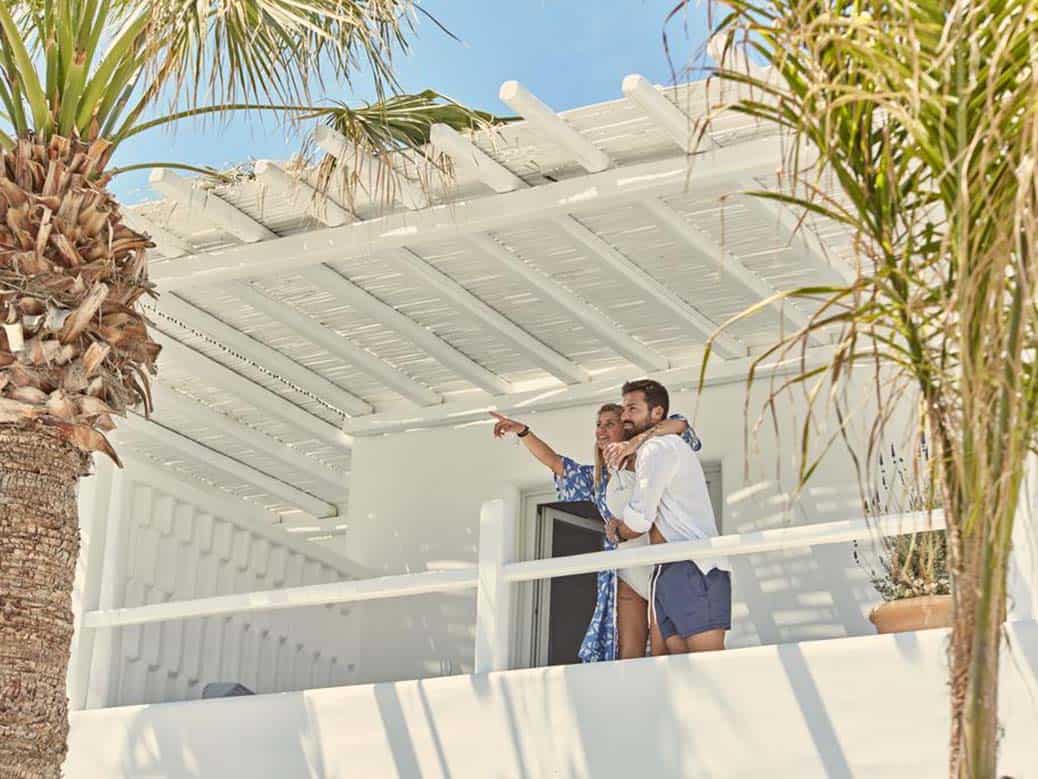 Example of great hotel photography showing happy couple on balcony at Mykonos Ammos hotel in Greece